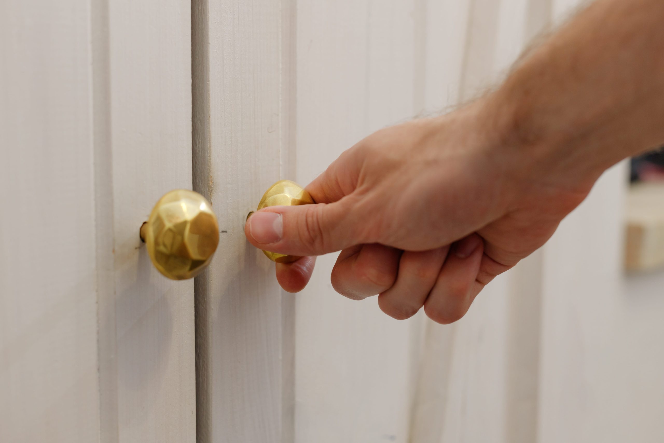 A amsculine hand grabbing a gloden cupboard door handle