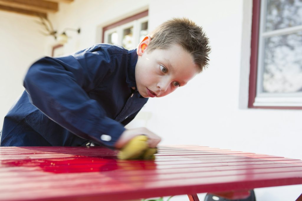 Boy concentrating on cleaning patio table